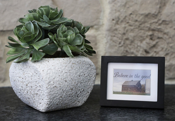 Framed picture with 'Believe in the good' quote.