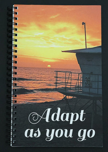 Journal with sunset over ocean and lifeguard tower design, featuring the text 'Adapt as you go'.