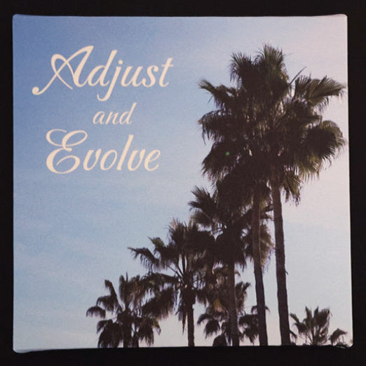 Canvas print with palm trees against a blue sky with 'Adjust and Evolve' text.