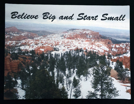Canvas print with scenic view of a snowy landscape with red rock formations and trees with 'Believe Big and Start Small' text.