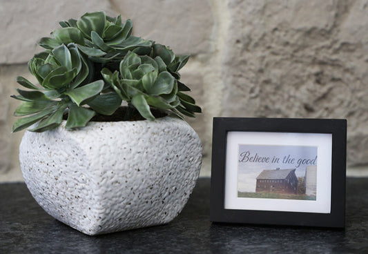 Framed picture with 'Believe in the good' quote.