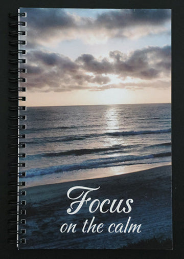 Notebook with a beach sunset scene and 'Focus on the calm' text.