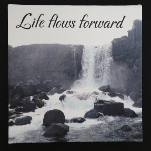 Canvas print with scenic waterfall with rocks with 'Life flows forward' text.