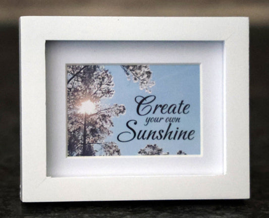 Framed picture with 'Create your own sunshine' quote.