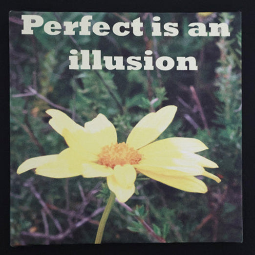 Canvas print with a yellow flower with 'Perfect is an illusion' text.