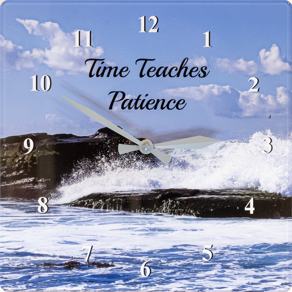 Square wall clock featuring a seascape scene with blue sky, clouds, ocean waves, and dark rocks. White Arabic numeral hour markers are placed over the scene, and the center reads the phrase 'Time Teaches Patience' in black script.