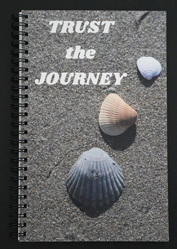 Journal with a scenic cover featuring a beach and seashells, with text 'Trust the Journey'.