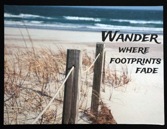 Canvas print with scenic beach scene with wooden fence and sand with 'Wander Where Footprints Fade' text.